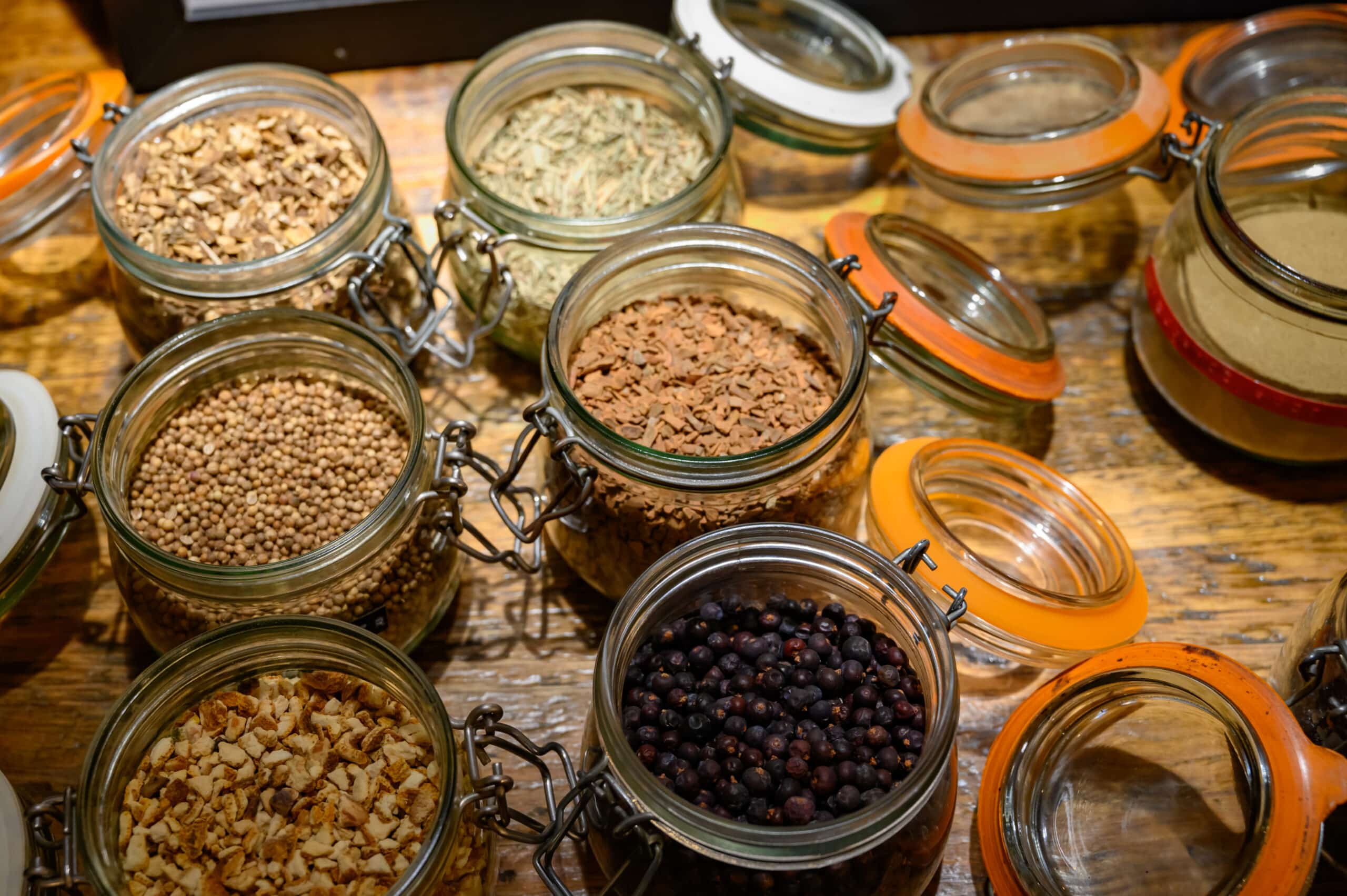 Tastes of gin, botanicals ingredients for gin distillery process, dried orange peels, juniper berries, heather, angelica, coriander, clove, cassia, liquorice in glass pots